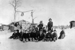 Skoltesamiske skolebarn sitter i snøen ved Pasvik-siidaens s