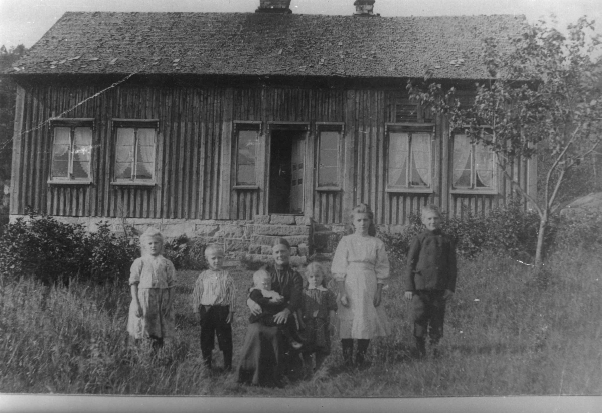 Dorte med sine barn i hagen utenfor huset. Sina, Marie, Jakob, Eivind, Gunnhild og Olav.