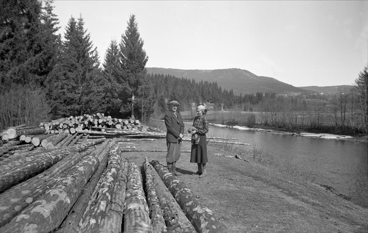 Sverre og Clara Ramstad står blandt tømmerstokker ved Lågen, Svarstad. Fotografert 1939.