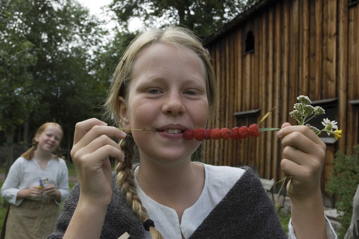 Levendegjøring på museum.
Ferieskolen uke 31, 2006. Jente spiser bringebær, som er tredd på et strå.
Norsk Folkemuseum, Bygdøy.