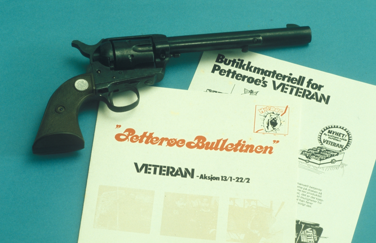 Reklamemateriell for Petterøes Veteran. Petterøe Bulletinen, broskyre om butikkmateriell for Petterøes Veteran og en revolver. Kampanje for tobakksmerket Petterøes Veteran 1975.