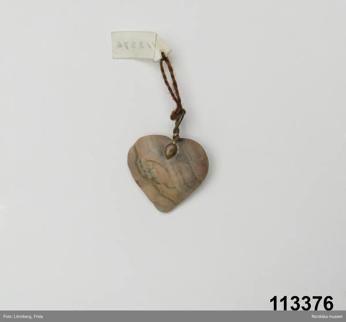 Huvudliggaren:
"Berlock av sten, hjärtformig med hängögla av koppar.
G. 6/4 1909 Elving, Anna Gunborg, fröken, Stockholm."