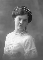 Portrett, kvinne med lys kjole og perlebånd i håret og om ha