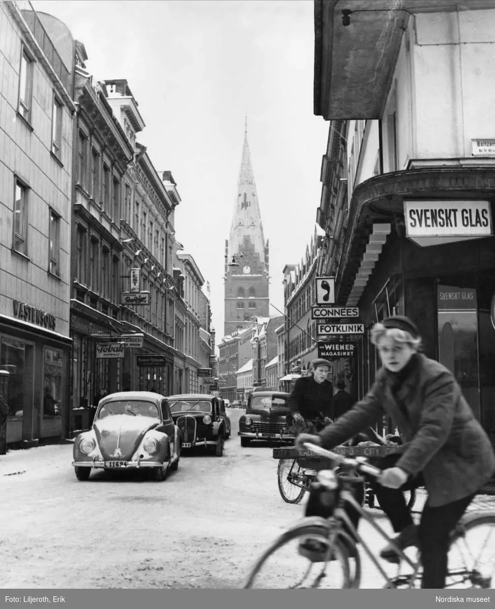 Bil- och cykeltrafik på vintrig stadsgata, Kalendegatan, i Malmö. I bakgrunden syns Sankt Petri kyrkas torn.
