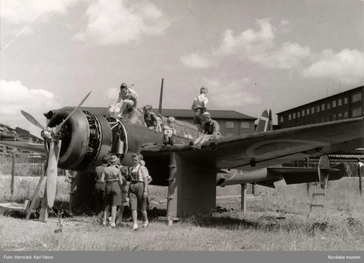 Lekplats. Barn leker vid gammalt militärflygplan (Saab B17) på Gärdet i Stockholm.