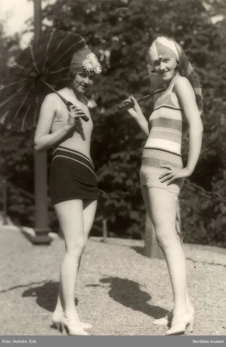 Två kvinnor i baddräkter, badmössor, skor och med parasoll. Nordiska Kompaniet.