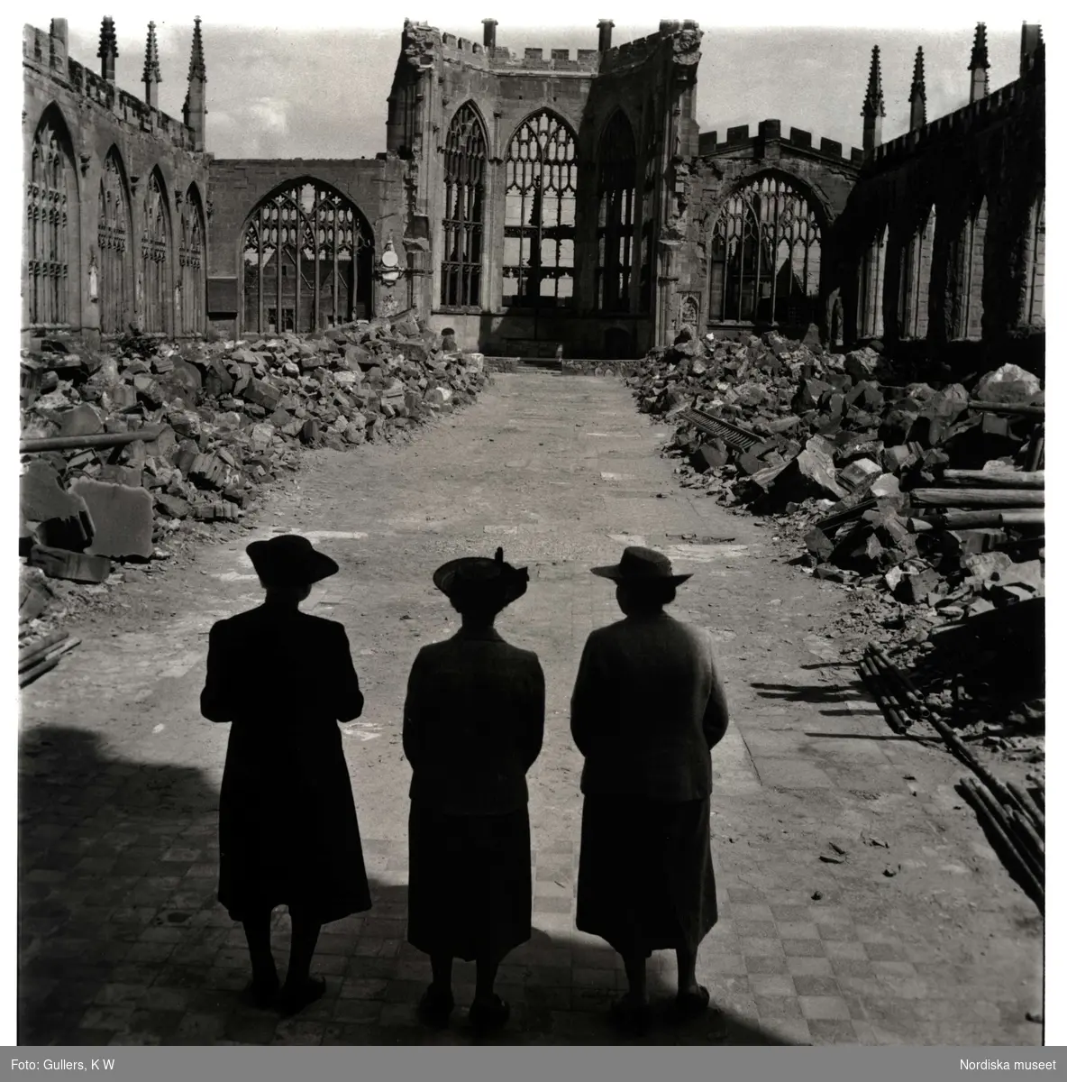 Tre kvinnor vid ruinerna av den sönderbombade katedralen i Coventry