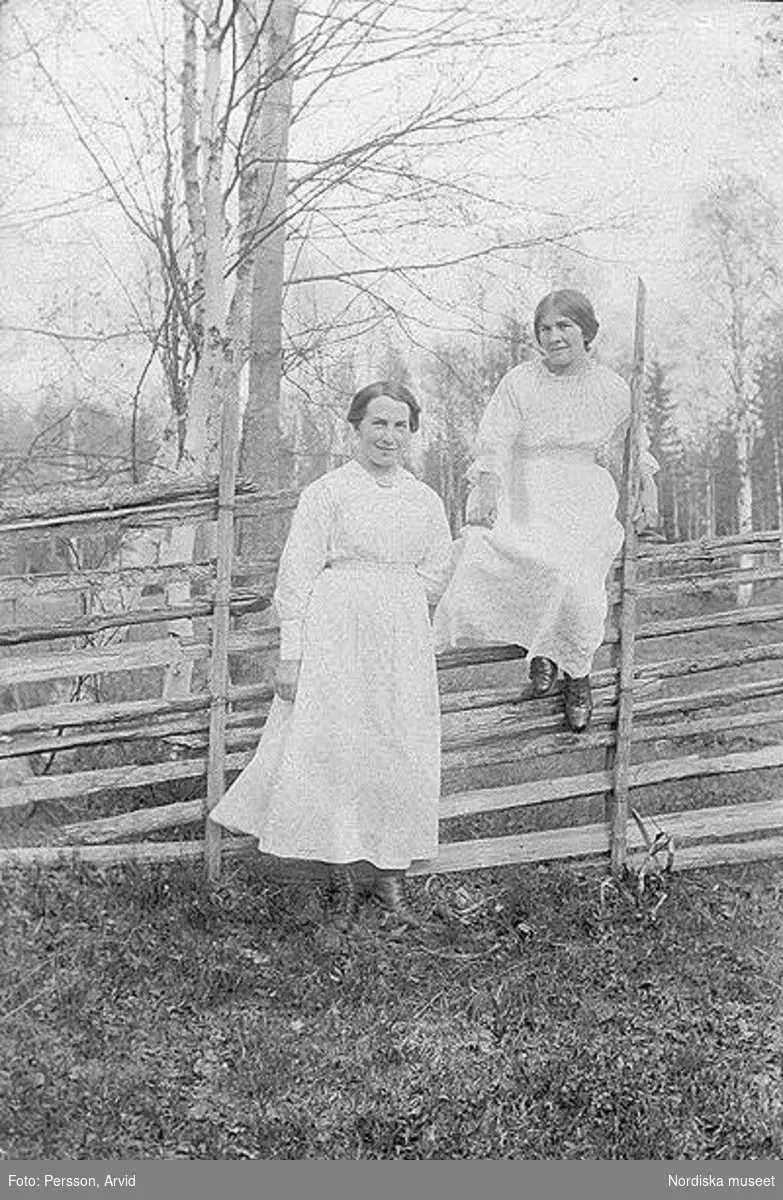 Porträtt av två kvinnor vid ett staket.
