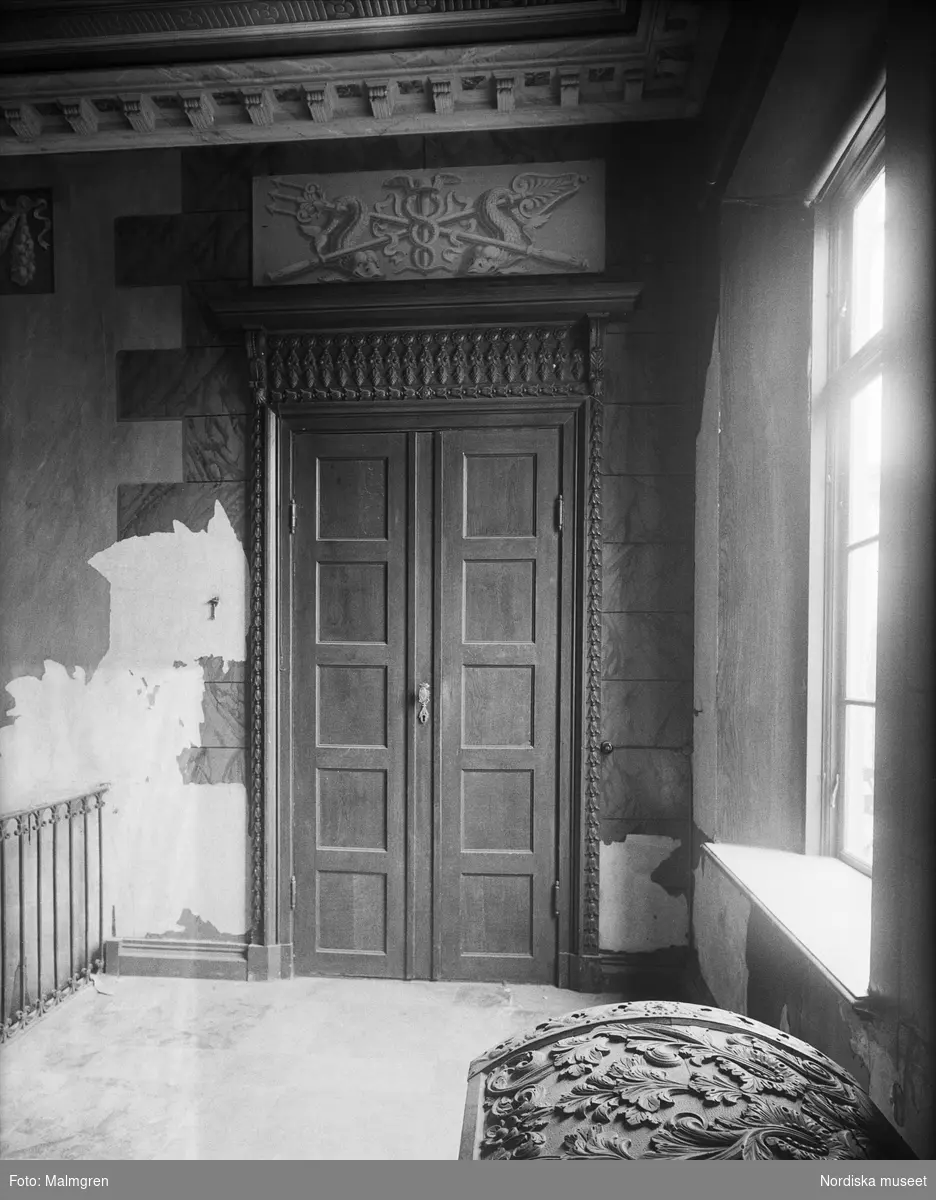 Detalj av interiör, dörrparti i övre hallen. Överstycket nu målat i brunt liksom dörren, förr grisaille. Skottorps slott, Höks härad, Skummeslövs socken, Halland.
