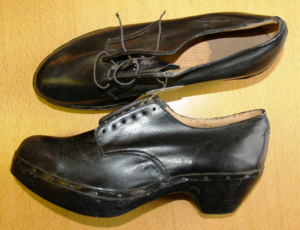 Sko i skai med papirtekstil fòr og tre såle. Pløse og snøring. Pløsen er skåret av på den ene skoen.