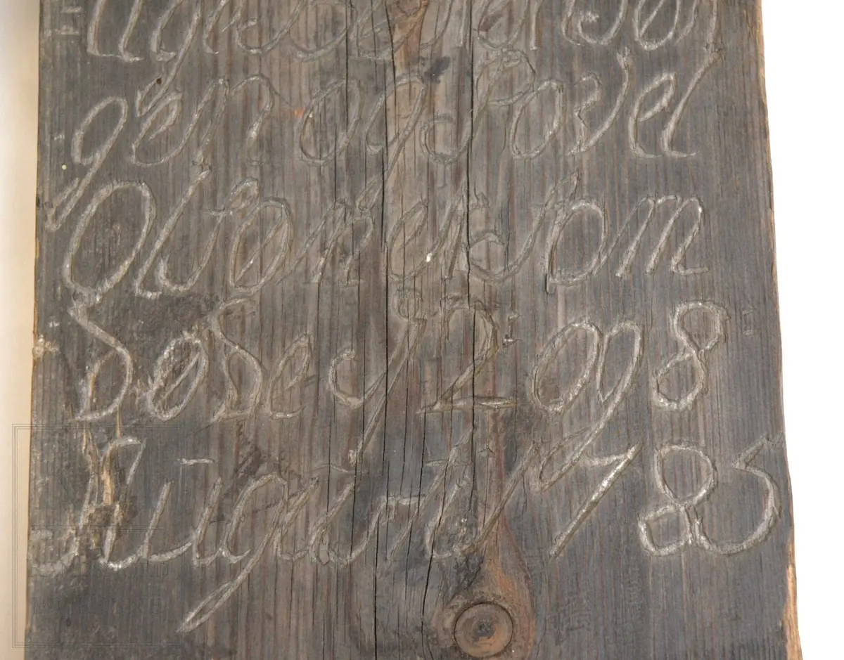 Gravminne med sekundært gavltak (påsatt i forb. med utstilling i våpenhuset i 1970). Innskriften skåret i treverket.
