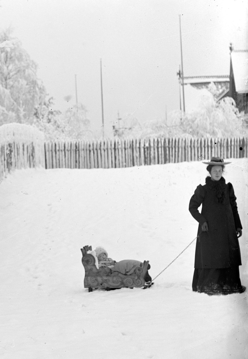 Johanne Alhaug drar sin datter, Eva (Høstmælingen) eller Margit, i en kjelke utenfor Holmsgården i Hamar. 