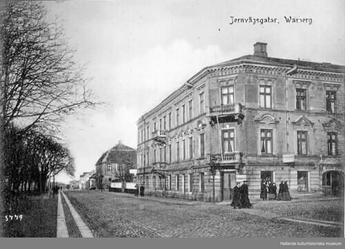 Vykort, "Jernvägsgatan, Warberg". Huset till höger ligger i kvarteret Prosten (nr 7), Västra Vallgatan-Kyrkogatan. Bilden är tagen mot norr. Idag heter gatan Västra Vallgatan.