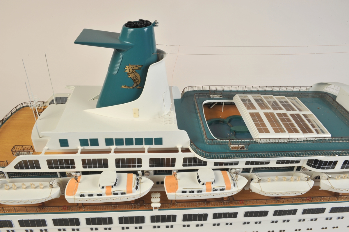 Hvitt passasjerskip med 6 livbåter på hver side, 2 av typen motorlaunche, rødt undervannsskrog, tynn grønn linje over vannlinjen, bvitt skrog, grønn skorstein med gyllen havhest.