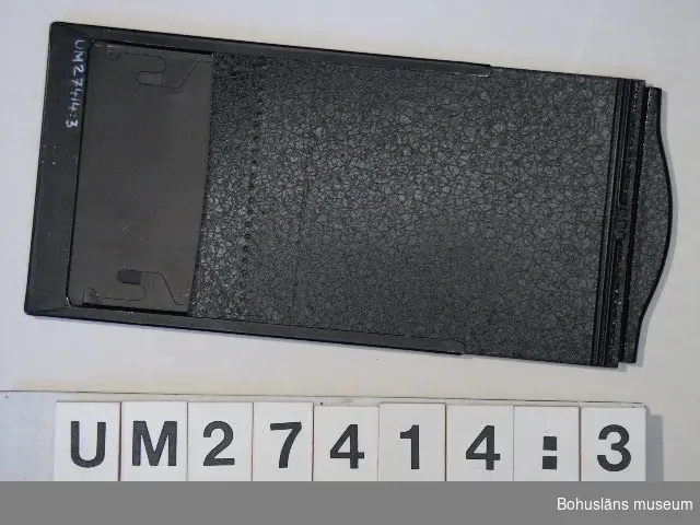 Fem svarta plåtkassetter för  filmexponering, H 6,2 x B 10 cm samt en fanerad träskassett med plats för två glasplåtar. H 30 x B 20,9 cm. Hör till kamera UM027413:1.