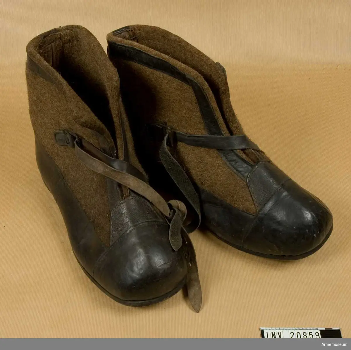 Grupp C.
Ur uniform för manskap, Första världskriget 1915-16, Tyskland.
Av mörkbrun filt, kantade med svart läder. På framsidan finns en rem med spännen som skorna spännes fast med. Sådana skor användes för vaktposten under vintern. De sattes ovanpå stövlarna.