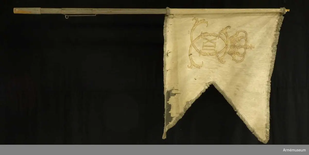 Duk: Tillverkad av vit damast och målad på båda sidor med Karl XII:s namnchiffer, dubbelt C med XII under sluten kunglig krona. Runt kanten frans av vitt silke. Fäst med sidenband och förgylda spikar.

Ursprunglig höjd var 105 cm, och ursprunglig bredd var 125 och 67 cm.

Stång: Tillverkad av furu, ovanför greppet finns sex räfflor och en förstärkande järnskena i varannan av dessa. Målad vit och försedd med löpande bärring. 

Spets av förgylld mässing.