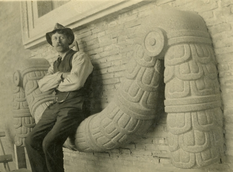 Bildhuggare Reinhold Pettersson sittande på en girlang gjord av huggen granit