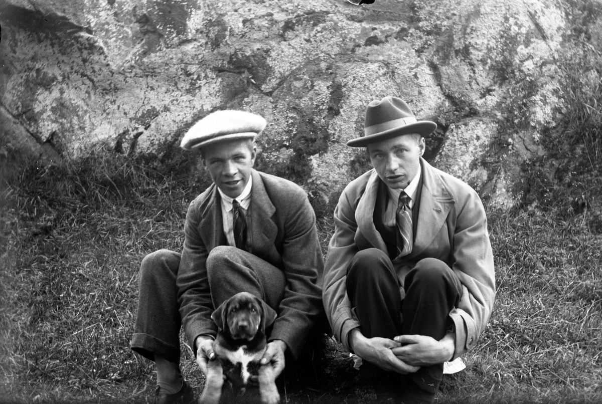 En man med en hund och Gustav Andersson (2) sitter med sten som bakgrund.