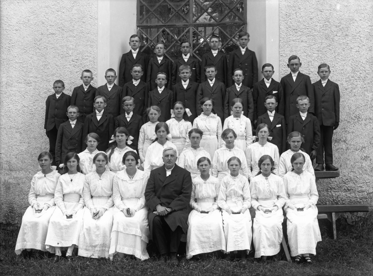 Konfirmandgrupp vid Simtuna kyrka, Uppland, förmodligen 23 juni 1916. I mitten kyrkoherde August Hylander (1852-1935).