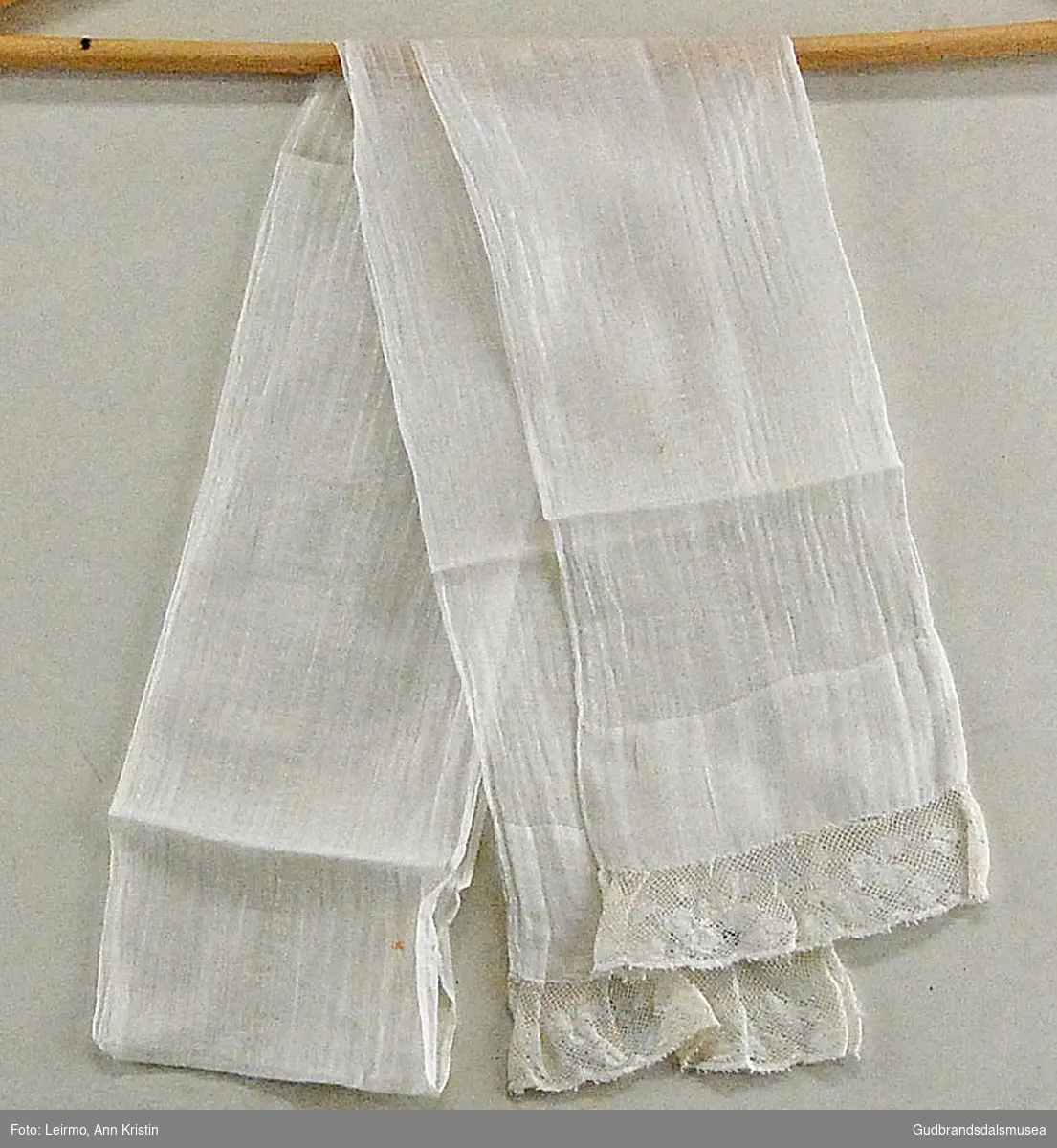 Hvitt tørkle/bånd i bomull med broderte endestykker. 
