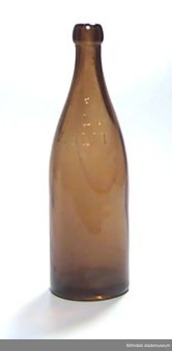 Brun flaska funnen på givarens tomt. S k knoppflaska, troligen för öl. Inpressat i glaset: "* L * 2/3 LITER".