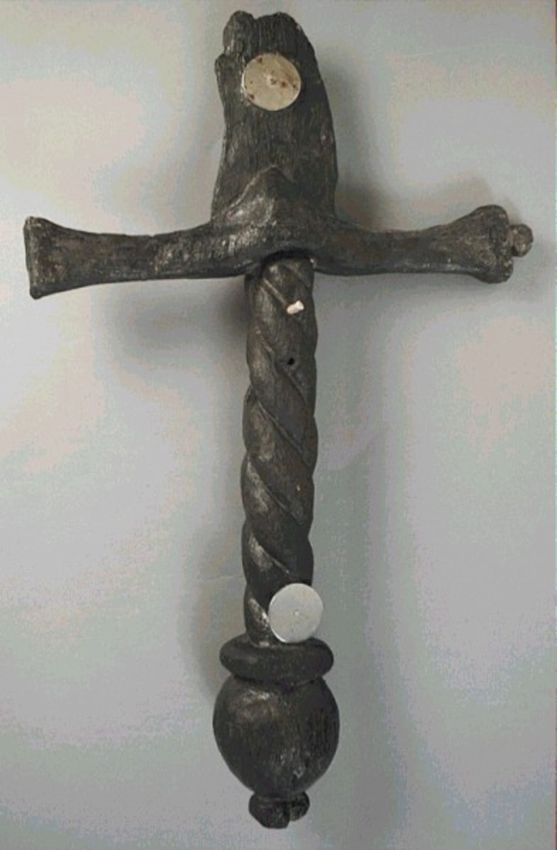 Skulpturdetalj, handfäste/kavel till svärd. tillhörande människofigur. Avlångt och spiralornerat, med en profilerad svärdsknapp i ena änden. I den andra änden finns ett urtag för svärdets parerstång.

Handfästet är ihopmonterat med den separat snidade parerstången och svärdsklingan, se fyndnummer 01456. Klingans tånge är fastsatt i handfästets urtag med en recent pinne eller liknande, vilken är instucken genom ett av två hål i handfästet.

Svärdsknappen är något skadad. I övrigt är skulpturdelen välbevarad, förutom mindre sprickor.

Det finns synliga spår av guld på skulpturdelarna (1997).