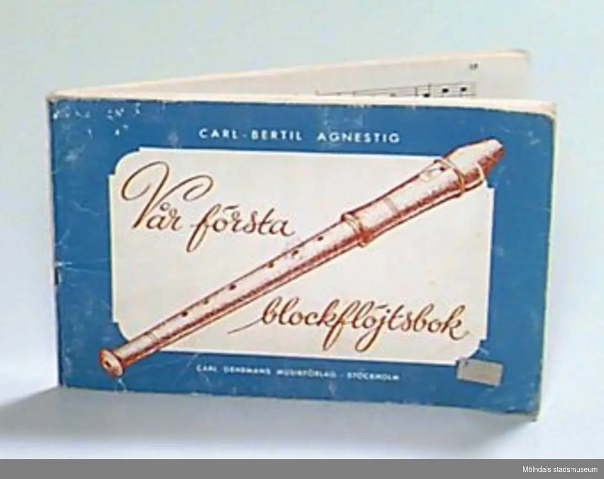 "Vår första blockflöjtsbok" av Carl-Bertil Agnestig. Omslaget är blått och vitt med text i vitt och rostrött samt en teckning av en blockflöjt i rostrött. Prislapp på framsidan.
På sidan tre finns stämplat: "Mölndals museum" samt skrivet med blyerts: "Xfa" (en ämneskod från museets bibliotek, där boken tidigare var placerad). 
På näst sista sidan är siffror skrivna med blyerts och på bakre pärmens insida är skrivet med blyerts: "G. Sven-Erik Johansson 3/10 -90".