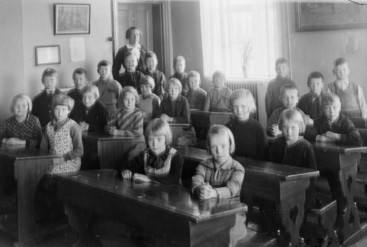 Lärarinnan Emma Aronsson med flickor och pojkar i ett klassrum på Kärraskolan, cirka 1935.