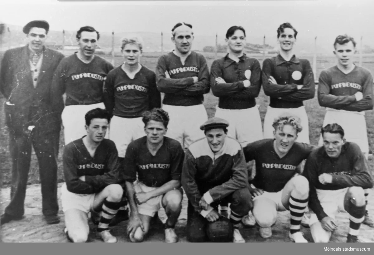 API fotbollslag uppställda vid fabriken A.B. Pumpindustri med fabriksreklam på tröjorna, 1950-talet. Med på bild: Rune Åkersson och Mossberg.
Spelarna är anställda på A.B. Pumpindustri.
