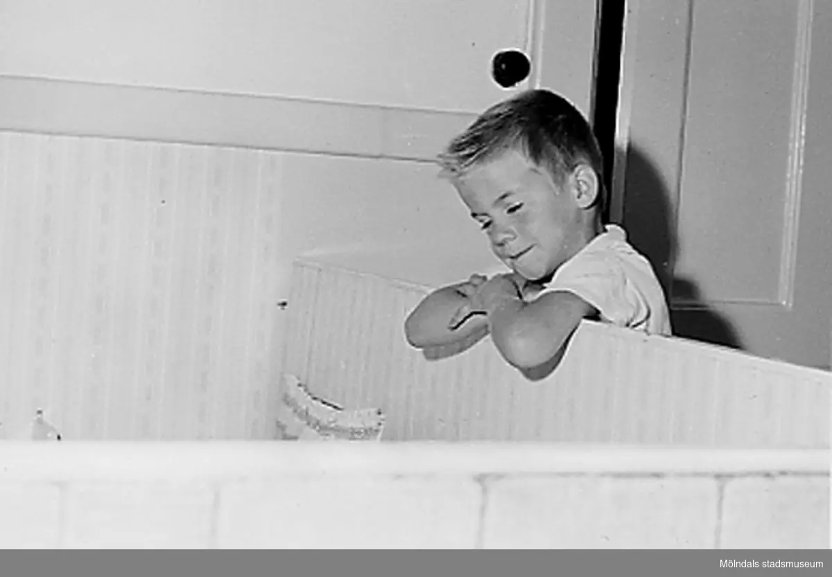 En pojke som lutar sig mot en koja vid Holtermanska daghemmet 1953.