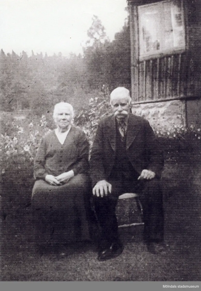 Johan Ferdinand (född: 1868) med en kvinna vid sin vänstra sida, okänt årtal. Troligtvis sitter de i deras trädgård framför huset. Relaterade motiv: 2007_0451 - 0453.