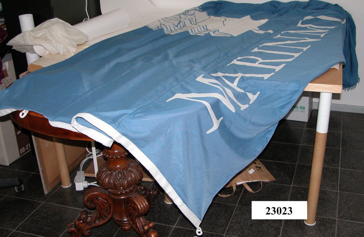Flaggans bakgrundsfärg är blå. På flaggans underkant finns texten: "Marinmuseum". Ovanför, strax till vänster, finns den dåvarande logotypen, en gallionsfigur. Text och gallionsfigur är tryckta i vitt. Flaggans yttre ände är något fransad