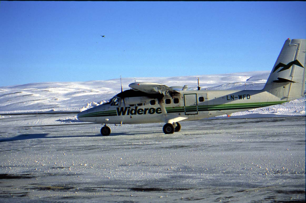 Lufthavn. 1 fly på bakken. 1 DHC-6 Twin Otter LN-WFD "Båtsfjord" fra Widerøe, sett fra siden. Fjell i bakgrunnen. Snø på bakken.
