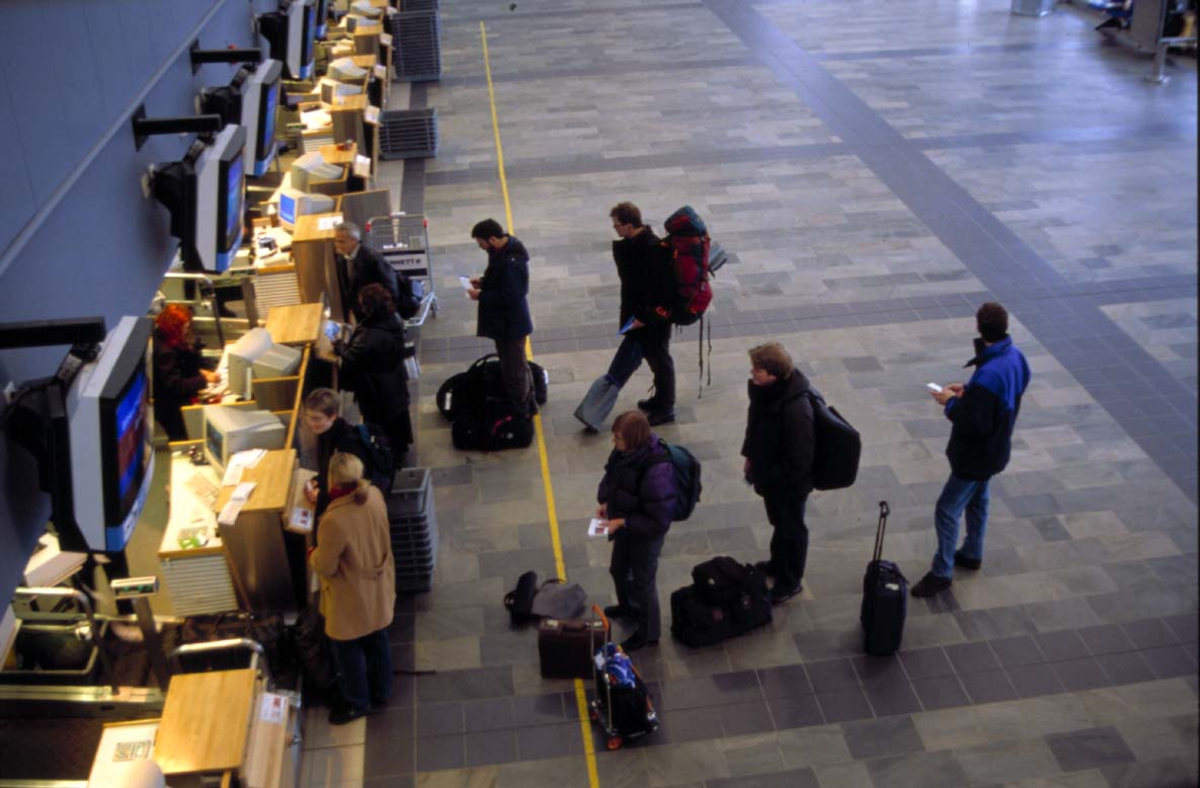 Lufthavn, flere personer i kø foran innsjekkingsskranken.
