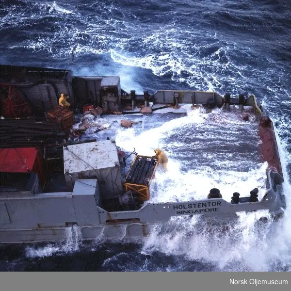 Supplybåten "Holstentor" i store bølger. Mannskapet jobber mens bølgene slår over dekk.
