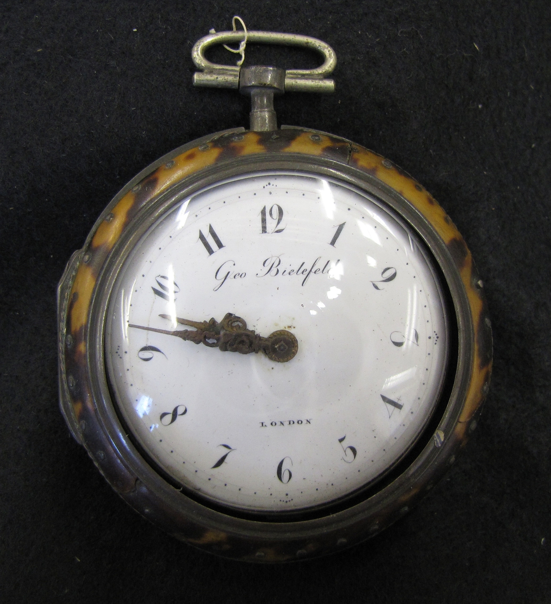 Klocka i sköldpaddboett, inskrift Geo Bielefeldt, London. Fickuret, vilken är en nyckeldragare, är troligen tillverkad under 1800-talets förra hälft.