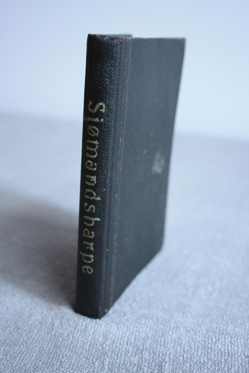 Svart liten bok med ordet sjømandsharpe trykka inn i ryggen.