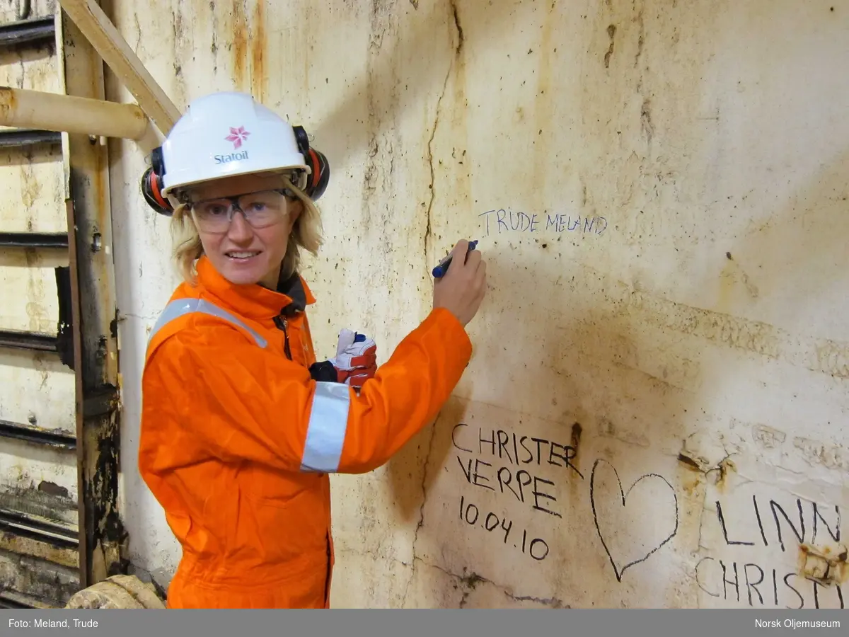 Trude Meland skriver sin signatur nederst i utstyrsskaftet  på havets bunn - Statfjord A.
