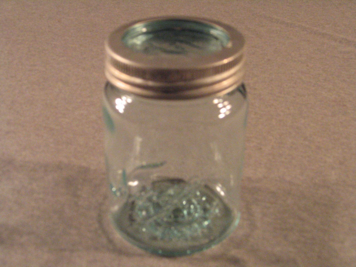 Rundt glas med skrukork av metall og glaslås