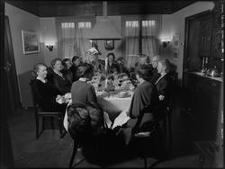 Kvinner festkledd rundt dekket bord til festmiddag i stue. U