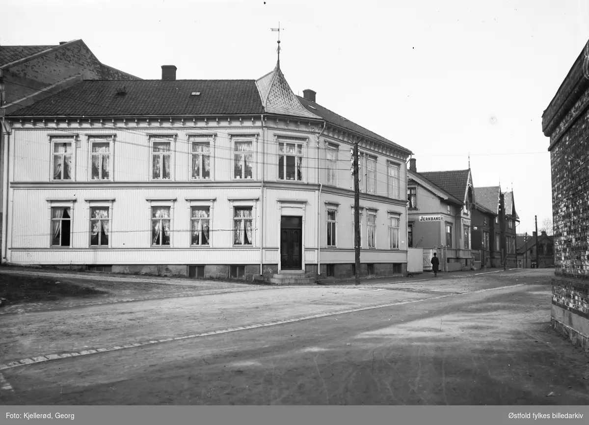 Gateparti fra Fredrikstad,  Hans Jacob Nilsens gate 17,, og til venstre går Welhavens gate.
Jernbanehotell, bygning til venstre har vindfløy med "1900".  
Trehusene i bakgrunnen er i dag erstattet av en boligblokk.

Disse husene lå i St. Olavsgate. Vi ser nr. 1 - 3 - 5 og 7. I nr. 7 lå Vangs pensjonat.