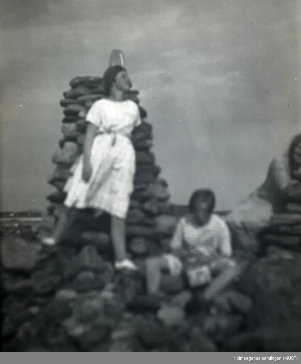 To jenter kledd i sommerkjoler ved en steinvarde. Antatt samme sted og tidspunkt som ST.K.HE 2007-011-0072 til -0081.