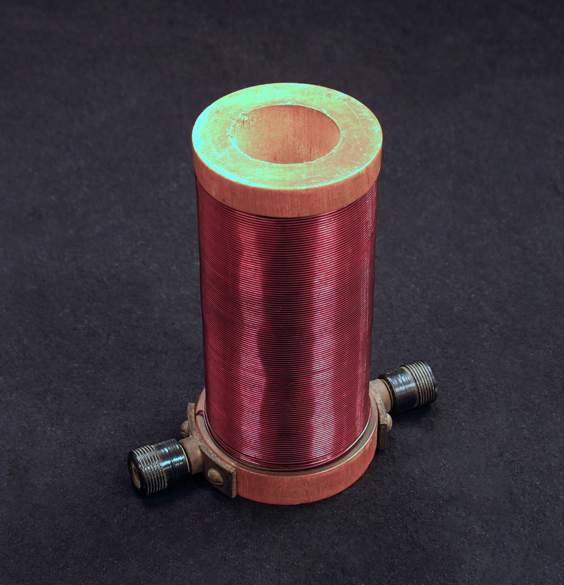 En cylinderformad elektromagnet i trä och metall med hål rakt igenom.
 Har troligen använts i fysikundervisning. 

Undervisningsmaterial från skolor i Vänersborg.