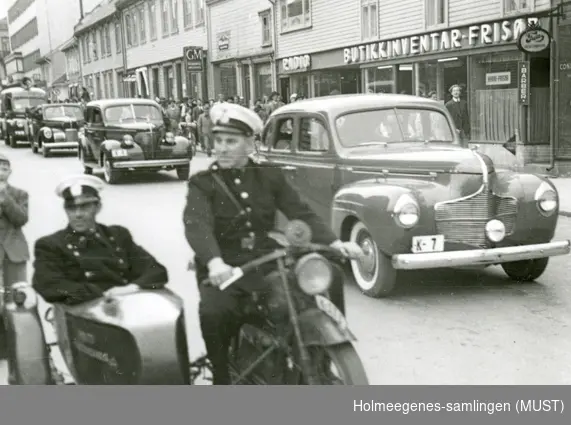 Politifolk kjørende på motorsykler med sidevogn og i biler.