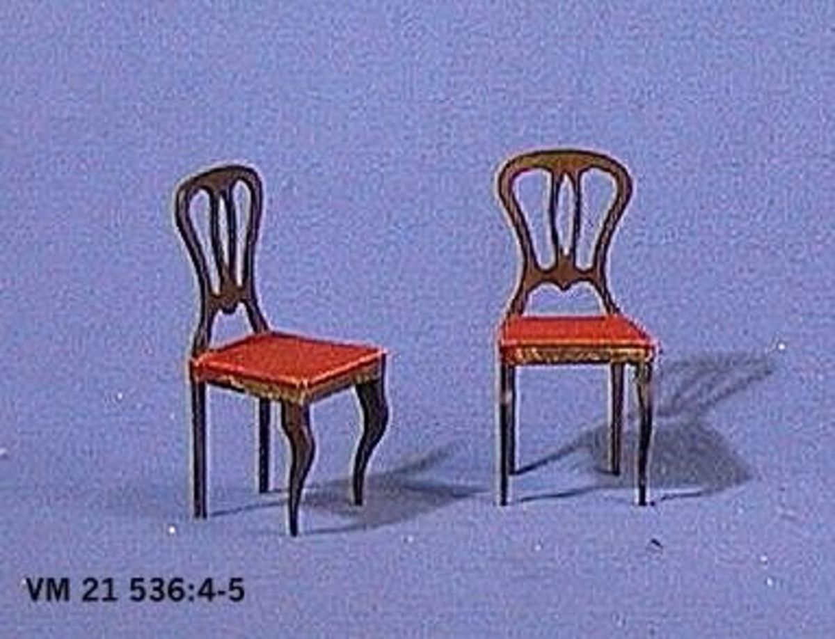 Stol i nyrokoko av brunbetsat trä, sitsen klädd med rött tyg och kanten klädd med  mönstrat papper. H. 10,2 cm. L.4,2 cm. B. 4,6 cm.
Stol, identisk med VM21536:04

Pinnstol, fyrbent, av omålat trä, rund sits klädd med rött tyg. Under stolen står ''Elsa 110''. H. 9,5 cm. B. 4,5 cm.

En samling dockmöbler och övriga inventarier till dockskåp. Ägarinnans far, Emanuel Hallén, var lärare på Slöjd- och Tekniska skolan i Vänersborg och han beställde dockskåpmöblerna från Vänersborgs fattiggård på Holmängen där de tillverkades av de intagna patienterna. Möblerna tillverkades 1891 till Beda och hennes syskon Signe, Elsa, Torsten och Gustav. Beda Hallén gifte sig senare med Hjalmar Persson, son till föreståndaren på Holmängens fattiggård Lars Persson. Givaren är dotter till ägarinnan.