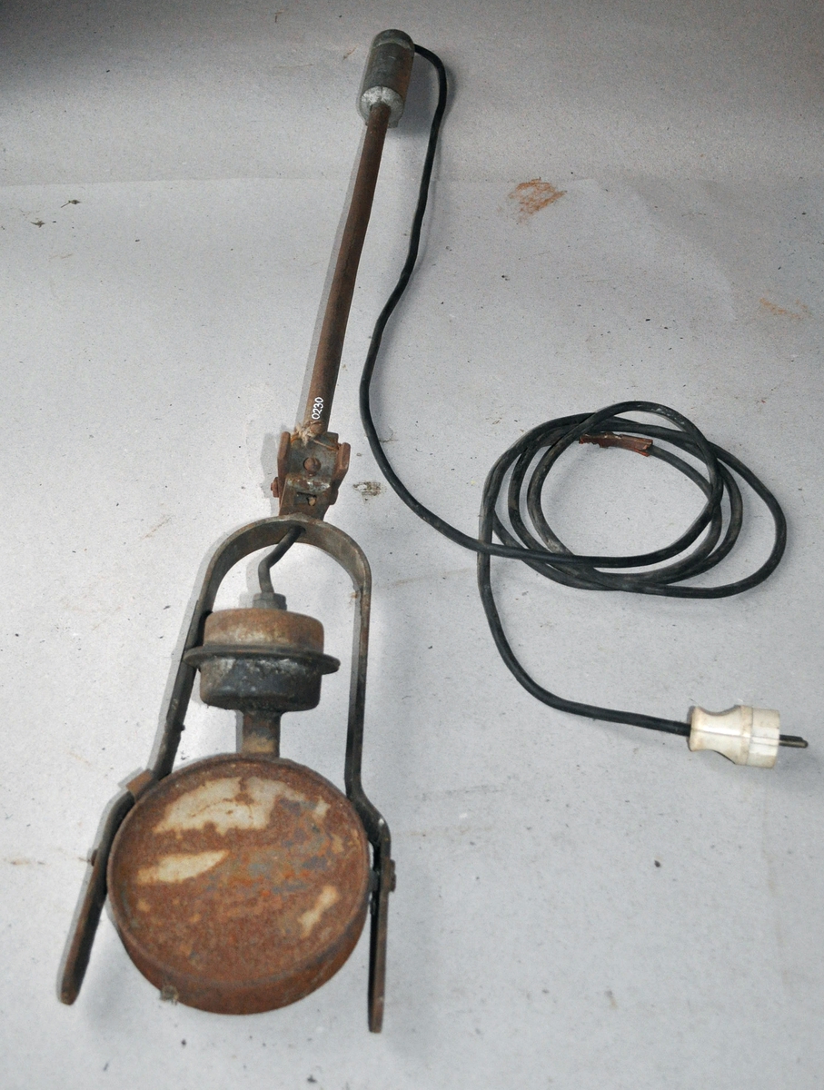 Motorvarmer bestående av et rundt varmeelement festet til to bøyler, som igjen er festet i et håndtak med ledning med stikkontakt i enden.
