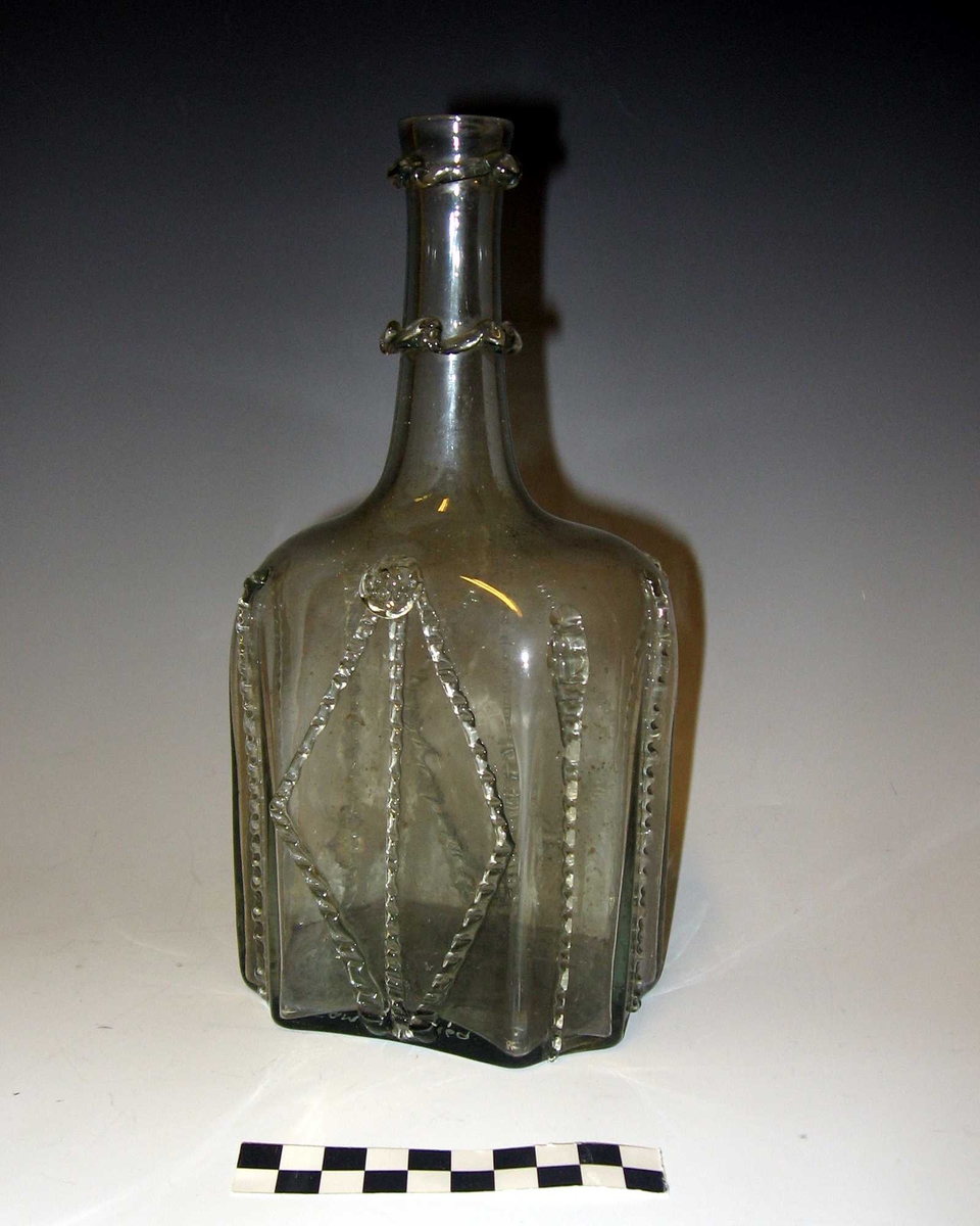 Fra kortet:
Flaske, karaffelformet. 4 kantet med brudte hjørner prydet med perleformede, bølgeformede baand. Har været itu, kittet.