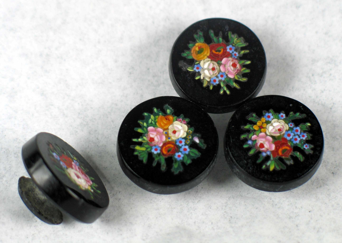 Fire svarte knapper i stein med innlagt blomsterdekor.