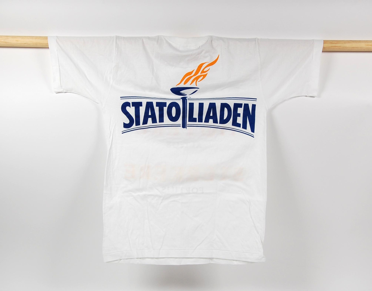 Hvit t-skjorte med flerfarget innskrift foran. Innskriften er inspirert av det olympiske motto, citius, altius, fortius. På ryggen på t-skjorten er det en logo for "Statoiliaden". I logoen inngår det en fakkel.